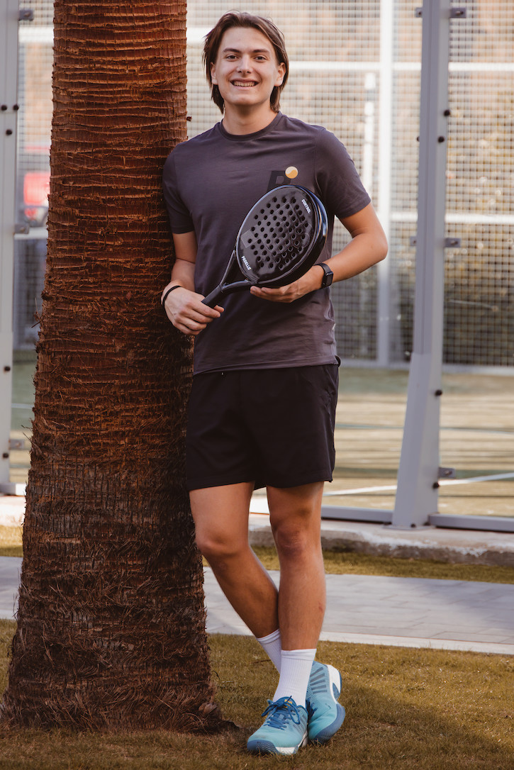 Eight shirts arranged on table in black, olive, grey, blue, white, red, mustard, and green.